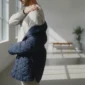 Person fasst sich an die schmerzende Schulter beim Anziehen einer Jacke