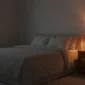 Ruhiges, abgedunkeltes Schlafzimmer am Abend mit Bett und Nachttisch